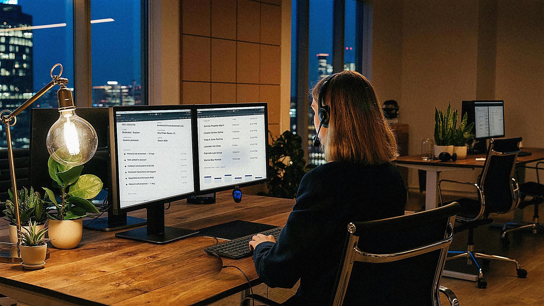 Operator wearing a headset working a CRM at night, photographed from behind